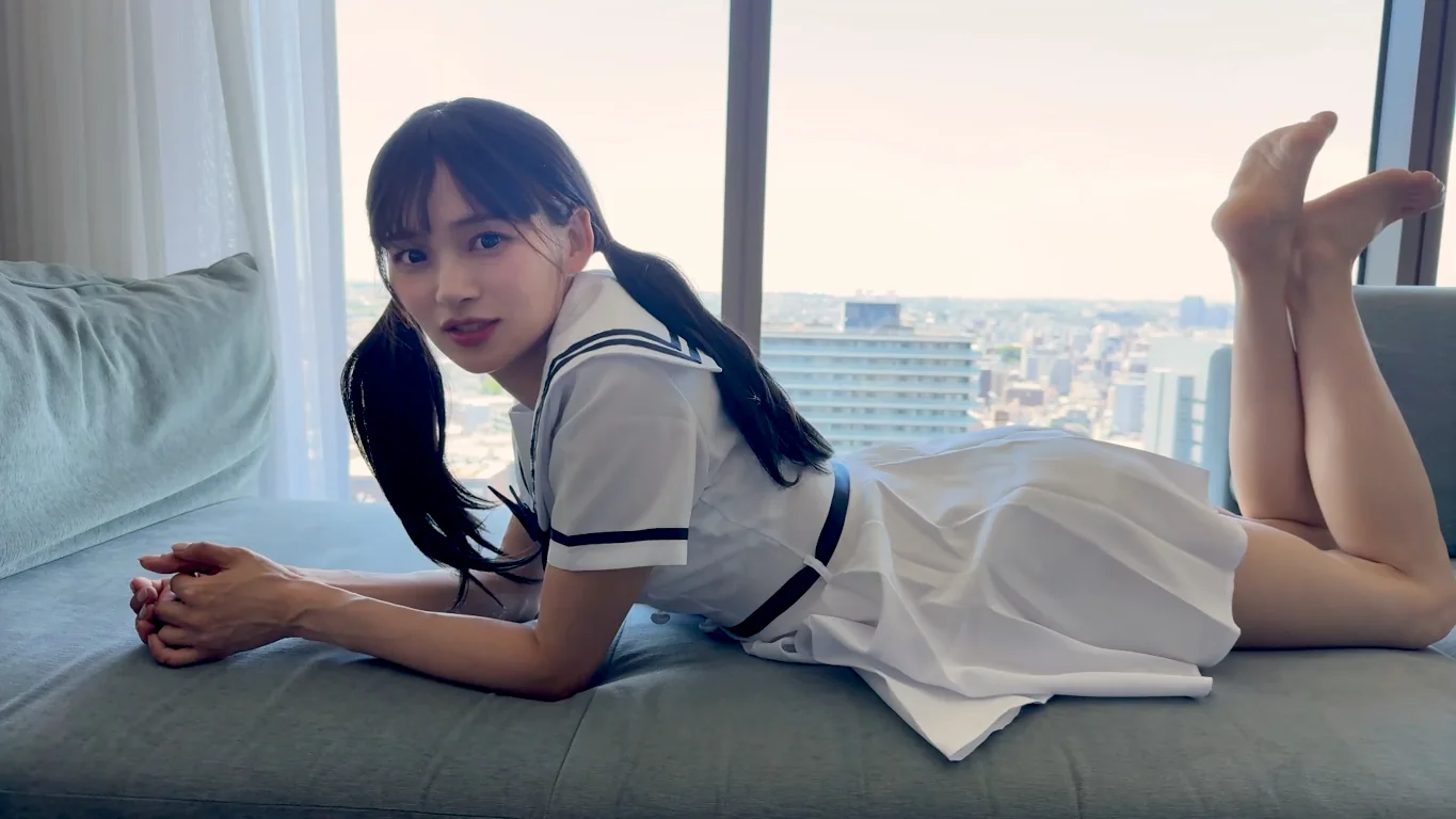 ホテルの窓辺で微笑むアミ（学生風の清楚な装い）